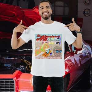 May include: A white short-sleeve t-shirt featuring a graphic print titled The Adventures of 10mm. The illustration depicts a beach scene with a person in a green bikini, a cartoon character, and a person wearing blue sunglasses with the text Hey, I know that guy from somewhere!
