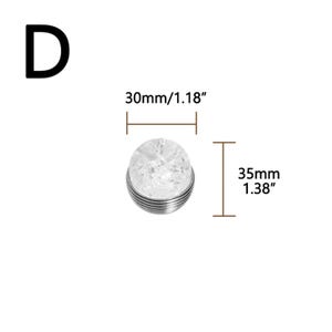 K&ouml;nnte beinhalten: Ein klares, rundes Dekorationsobjekt mit rissiger, kristalliner Optik, das 3,5 cm hoch und 3 cm im Durchmesser misst. Das Objekt hat einen silberfarbenen, gerippten Sockel. Der Buchstabe "D" befindet sich in der oberen linken Ecke.