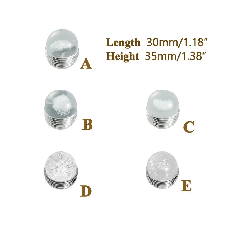 K&ouml;nnte beinhalten: F&uuml;nf dekorative Glascabochons mit silberfarbenen Metallsockeln. Die Cabochons haben verschiedene Designs, darunter ein Wolkeneffekt, ein kristallartiges Muster und ein glitzerndes Aussehen. Die L&auml;nge betr&auml;gt 30 mm, die H&ouml;he 35 mm.