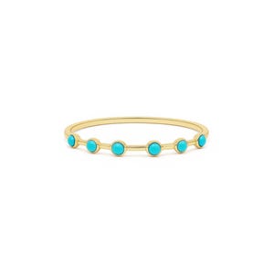 Op de afbeelding: Een delicate goudkleurige armband met zeven ronde, heldere turkooizen stenen. De stenen zijn gelijkmatig verdeeld over de dunne band, wat een minimalistisch en elegant ontwerp creëert. De armband staat tegen een witte achtergrond.