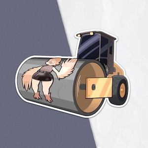 Op de afbeelding: Een sticker met een stripfiguur op een wals. Het personage heeft lichtbruin haar en draagt een bruin topje en een zwarte rok. De wals is grijs en geel, met een zwarte cabine en een grote wals.