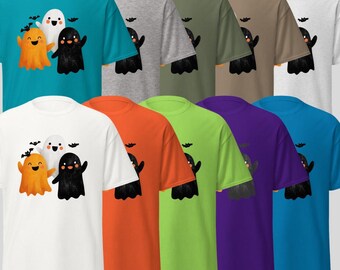 May include: A collection of colorful t-shirts featuring a Halloween-themed design. Each shirt displays a graphic of three cartoon ghosts in orange, white, and black, with bats above them. The shirts come in various colors, including teal, gray, green, brown, and white.