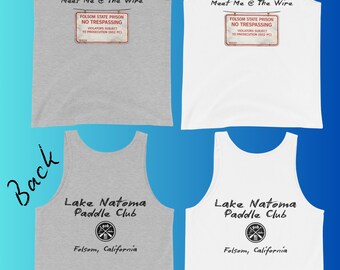May include: Two tank tops, one gray and one white, with text and graphics. The front of each tank top reads "Meet Me @ The Wire" above a sign that says "FOLSOM STATE PRISON NO TRESPASSING". The back of each tank top says "Lake Natoma Paddle Club" and "Folsom, California".