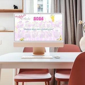 Puede incluir: Una pantalla de ordenador muestra un calendario de 2026 con un diseño floral. El calendario tiene un fondo lila claro con meses y fechas, y el texto "La abundancia fluye donde crece la gratitud." El ordenador está sobre un escritorio blanco con teclado y ratón.