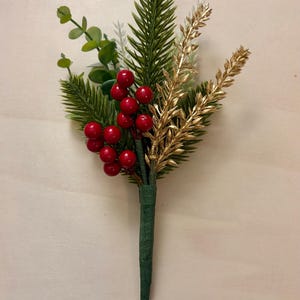 May include: A festive floral arrangement featuring green pine needles, gold-colored sprigs, and bright red berries. The stems are wrapped in green paper, creating a classic holiday or winter theme. This decorative piece is suitable for various craft projects.