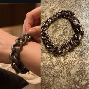 Puede incluir: Una pulsera de cadena de metal de cañón de fusil con un diseño de eslabones gruesos. La pulsera presenta secciones adornadas con pequeños cristales brillantes. El cierre tiene forma rectangular con un logotipo.