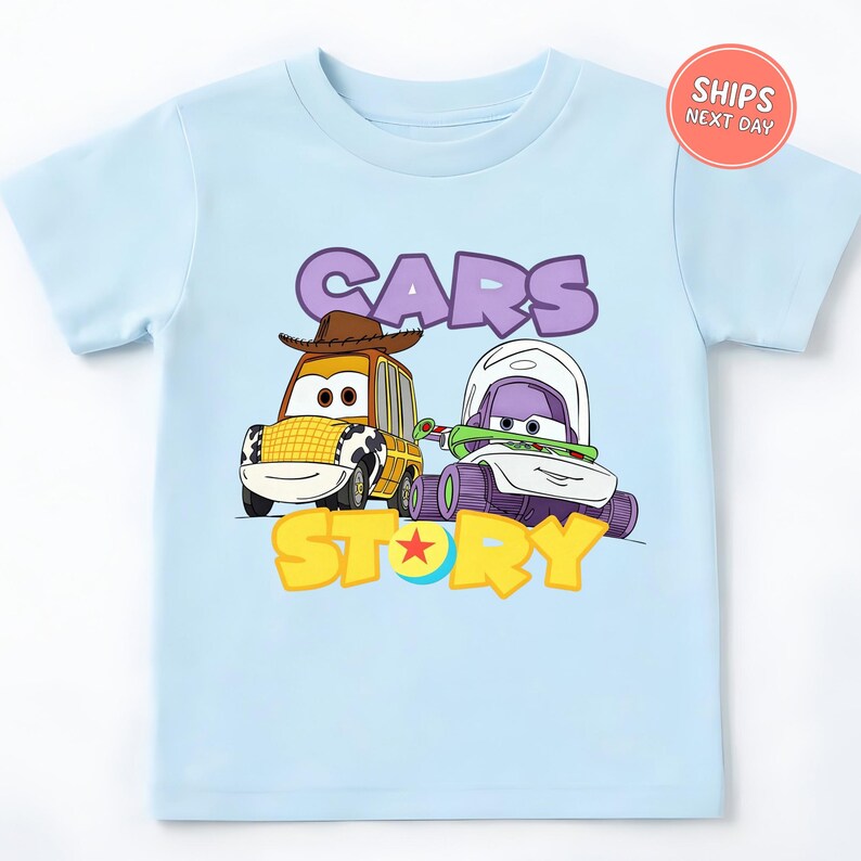 A light blue t-shirt with a graphic design featuring two cartoon cars, one yellow and one purple, along with the text "CARS STORY".