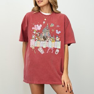 A woman wearing a red t-shirt with a Disney-themed graphic design.