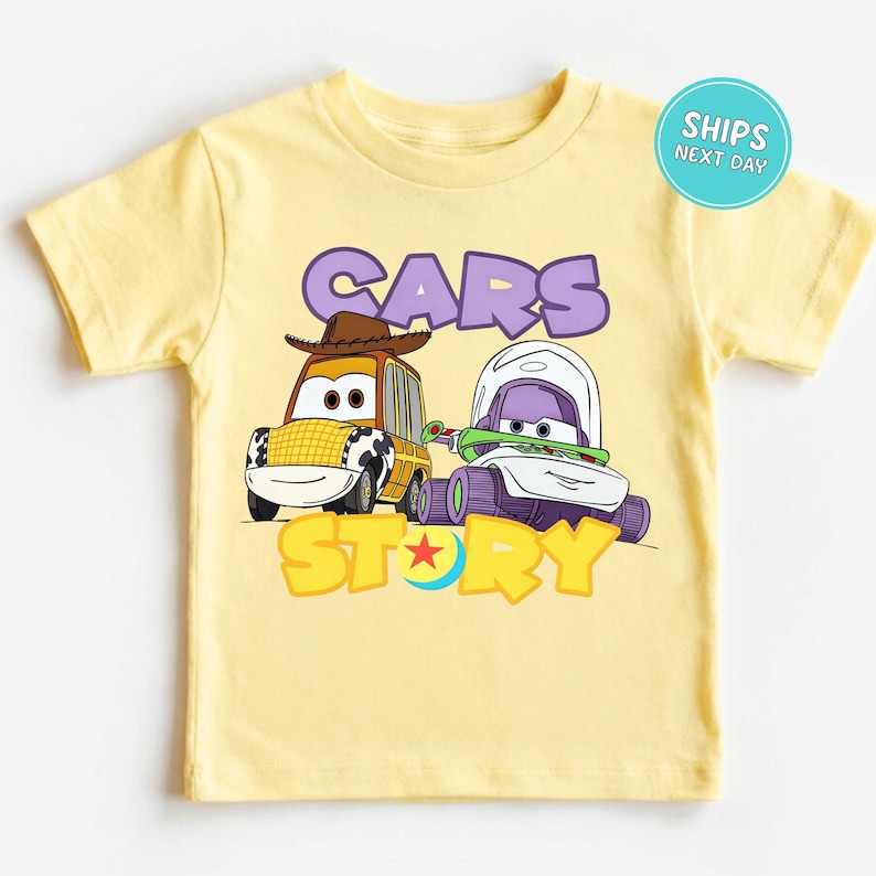 A yellow t-shirt with a cartoon image of two cars, one with a cowboy hat and the other with a green and purple design, along with the text "CARS STORY".