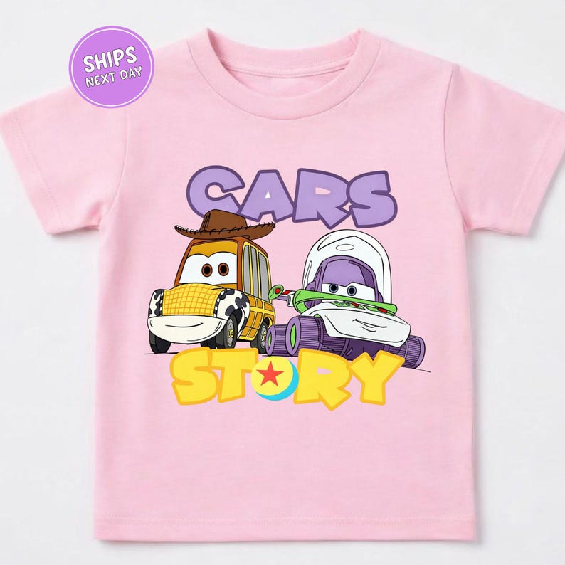 A pink t-shirt with a cartoon image of two cars, one yellow and one purple, along with the text "CARS STORY" printed on it.