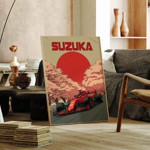 Puede incluir: Póster enmarcado con un coche de carreras rojo en una pista, la palabra "SUZUKA" en rojo sobre un sol rojo. El fondo muestra cerezos en flor. El póster está en un marco de madera.