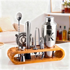 May include: A stainless steel bar tool set with a wooden bamboo holder. The set includes a cocktail shaker with the name "KAELAN", a strainer, a spoon, a jigger, a muddler, tongs, a bottle opener, and a corkscrew.