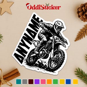 May include: Black and white sticker featuring a motocross rider on a dirt bike. The sticker has the text "ANYNAME" in a bold, slanted font. The rider is wearing a helmet and goggles. The sticker is a graphic design.