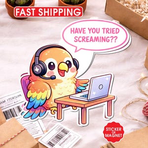 May include: A colorful cartoon sticker or magnet featuring a bird wearing a headset and using a laptop. The bird has a speech bubble that says, "HAVE YOU TRIED SCREAMING??" The sticker is on a table with other items, including a cactus and a box.