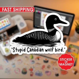 May include: A black and white sticker or magnet featuring a stylized illustration of a loon. The sticker includes the text "Stupid Canadian wolf bird."
