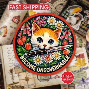 May include: A round sticker or magnet featuring a cat with orange and white fur, blue eyes, and a knife in its mouth. The design includes flowers and the text "BECOME UNGOVERNABLE" in a circular layout.