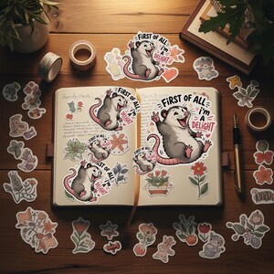 Puede incluir: Una colecci&oacute;n de pegatinas y art&iacute;culos de papeler&iacute;a dispuestos sobre una superficie de madera. Las pegatinas presentan un dibujo de zarig&uuml;eya con el texto "First of all, I'm a Delight". Otras pegatinas incluyen dise&ntilde;os florales y de animales.