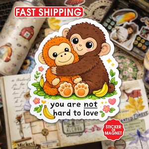 May include: A sticker or magnet featuring two cartoon monkeys hugging, surrounded by flowers and bananas. The text "you are not hard to love" is included. The sticker has a white border and a red circle that says "Sticker or Magnet".