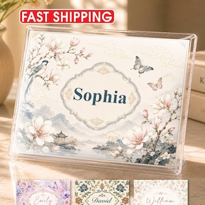 May include: A clear acrylic rectangular frame displaying a personalized print with the name Sophia in the center. The artwork features a landscape with magnolia flowers, a bird, and butterflies. Three additional rectangular prints with the names Emily, David, and William are shown below the frame.