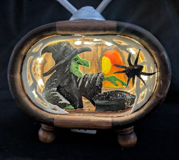 A scratch-built, one-of-a-kind witch-and-cauldron diorama housed inside a retro TV shell that glows — pure 'a real human made this weird beautiful thing' energy.