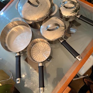 Może przedstawiać: Zestaw trzech ceramicznych kubków z nakrapianym, matowym wykończeniem. Kubki są w odcieniach kremu, jasnoszarym i ciemnoszarym. Każdy kubek ma prosty, minimalistyczny design i zaokrąglony uchwyt.