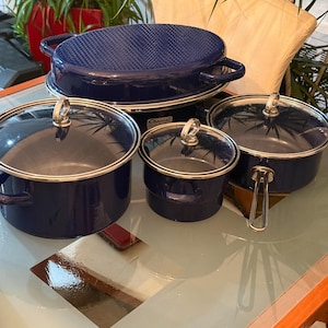 Puede incluir: Un juego de utensilios de cocina esmaltados de color azul oscuro de la marca Chantal, que incluye una asadera ovalada grande con tapa texturizada, dos ollas redondas con tapas de vidrio y una cacerola más pequeña con tapa de vidrio.