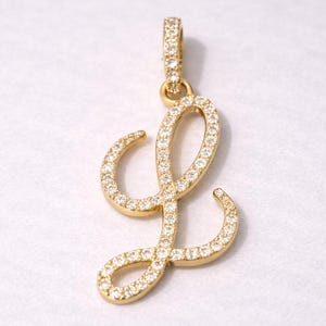 Peut inclure: Pendentif doré en forme de lettre "L", incrusté de petits brillants étincelants. Le pendentif est doté d'une boucle en haut pour une chaîne. Le design est élégant et convient aux bijoux.