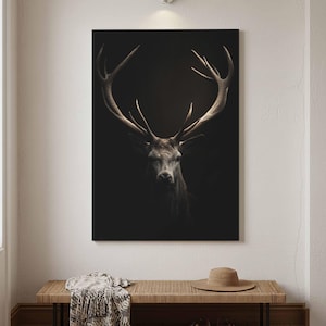 May include: A rectangular wall art print featuring a high-contrast portrait of a stag with large, detailed antlers. The animal is rendered in shades of brown and grey against a solid black background, creating a dramatic and focused visual effect.
