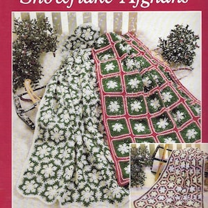 May include: A craft book cover titled Crocheted Snowflake Afghans featuring two blankets with snowflake motifs. One blanket has white snowflakes on a dark green background, and the other has white snowflakes on a red and green grid pattern.