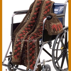 May include: A crochet blanket and matching bag featuring a dark brown, light brown, and rust red color scheme with a textured pattern. The blanket is draped over a wheelchair, and the small bag hangs from the armrest. Text reads Tini Dancer Vintage.