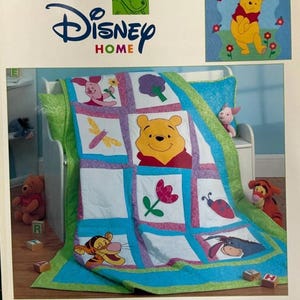 May include: A craft book titled Disney Home Pooh & Friends Patchwork Parade 13 Projects. The cover features a patchwork quilt with squares depicting Winnie the Pooh, Piglet, Tigger, Eeyore, a ladybug, a flower, and a dragonfly, with blue and green borders.
