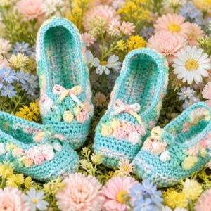 May include: Two pairs of handmade crochet slippers in a variegated pastel yarn featuring shades of turquoise, soft pink, and cream. Each slipper has a rounded toe, a low-cut opening, and a small decorative bow detail on the front of the upper.