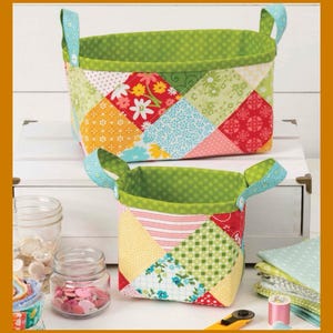Puede incluir: Dos cestas de almacenamiento de tela con un diseño de patchwork colorido con varios patrones florales y geométricos en rojo, amarillo, azul y verde. Cada cesta tiene un forro interior de lunares verde brillante y dos asas florales azul claro.
