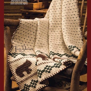 May include: A cream-coloured crocheted afghan featuring a repeating pattern of dark brown bears and dark green geometric shapes. The text "Watching out for bears? Invite them inside on this warm and woolly afghan." and "Tini Dancer" are visible.