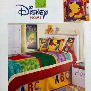 May include: A Leisure Arts craft book titled Peek-A-Boo Pooh Patchwork featuring 12 projects. The cover displays a bed decorated with Winnie the Pooh themed patchwork quilts, pillows, and a yellow bed skirt with large purple and blue ABC letters.