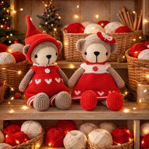 Puede incluir: Dos osos de peluche de ganchillo hechos a mano con trajes rojos y detalles blancos, sentados en un estante de madera. Uno lleva un gorro puntiagudo, el otro un lazo. Cestas de ovillos de lana rojos y crema y un pequeño árbol de Navidad en el fondo.