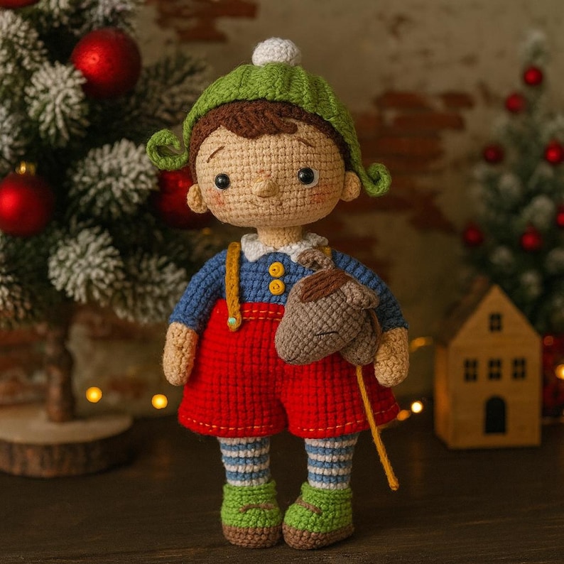 Puede incluir: Mu&ntilde;eca de ganchillo hecha a mano con camisa azul, pantalones cortos rojos y zapatos verdes. La mu&ntilde;eca tiene un sombrero verde y sostiene un caballo de palo marr&oacute;n. La mu&ntilde;eca est&aacute; frente a un &aacute;rbol de Navidad.
