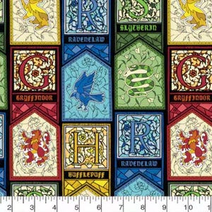 May include: Fabric featuring colorful panels with the names of Hogwarts houses: Gryffindor, Ravenclaw, Slytherin, and Hufflepuff. Each panel has a house emblem and name. The fabric is black with a ruler at the bottom.