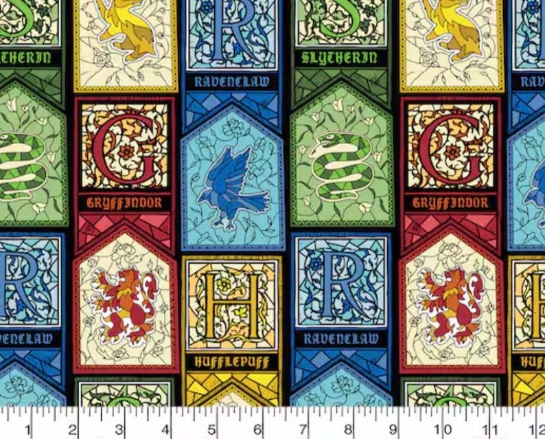 May include: Fabric featuring colorful panels with the names of Hogwarts houses: Gryffindor, Ravenclaw, Slytherin, and Hufflepuff. Each panel has a house emblem and name. The fabric is black with a ruler at the bottom.
