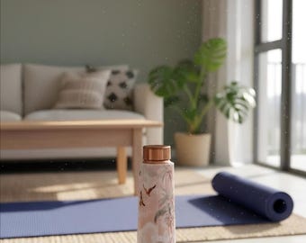 May include: A stainless steel water bottle with a rose gold lid and a pink and white tropical design featuring palm trees and birds. The bottle is cylindrical and sits on a wooden surface. A blue yoga mat is in the background.