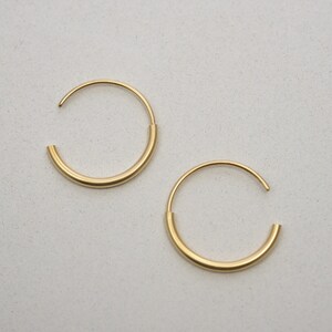 May include: A pair of gold hoop earrings. The hoops are thick and have a smooth, polished finish.