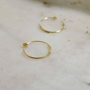 May include: A pair of gold hoop earrings. The earrings are simple and elegant, with a thin, delicate design.