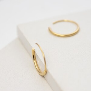 May include: A pair of gold hoop earrings. The earrings are simple and delicate, with a smooth finish.