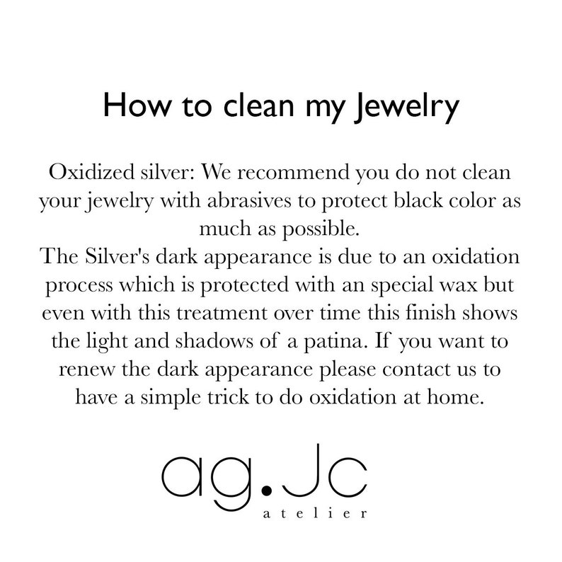 May include: Text explaining how to clean oxidized silver jewelry. The text recommends not using abrasives to protect the black color. It also explains that the dark appearance is due to an oxidation process protected by a special wax. The text also mentions that the finish shows light and shadows of a patina over time. The text concludes by saying that if you want to renew the dark appearance, you can contact the company for a simple trick to do oxidation at home. The text is followed by the company name "ag.Jc atelier".