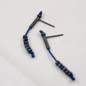 Pair of 38 mm length pendant earrings handmade in oxidized sterling silver tube with a blue silk cord threaded through the center for hanging Miyuki beads in Picasso cobalt blue. Designed and crafted by hand in Paris by A g J c