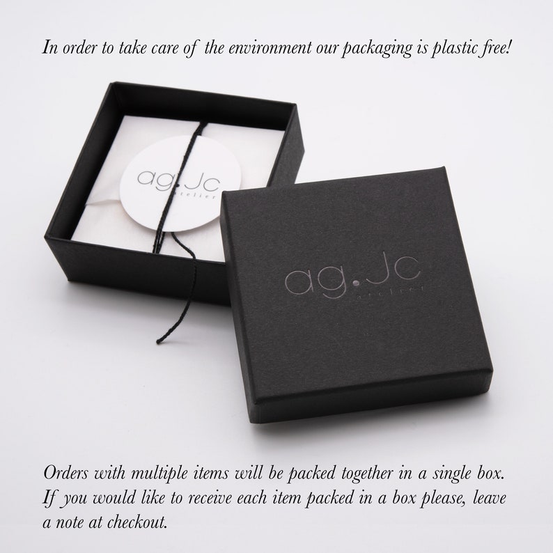 May include: A black jewelry box with the text "ag.Jc" printed on the top. The box is open and the inside is lined with white paper. The text "agJc" is printed on a white circle inside the box.