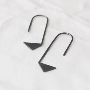 May include: A pair of black triangle shaped earrings with a simple curved design.