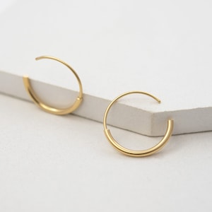 May include: A pair of gold hoop earrings. The earrings are simple and elegant, with a smooth, polished finish.