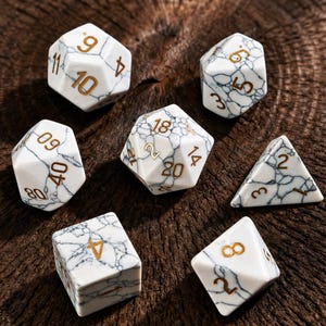 May include: Set of seven white and black marbled polyhedral dice with gold-colored numbers. The dice are arranged on a dark brown, textured wooden surface. The dice are for role-playing games.
