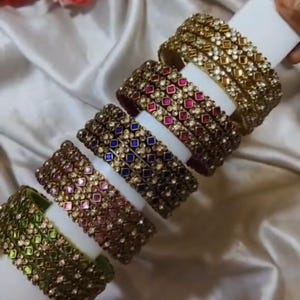 May include: A white ceramic mug with a black handle and the text "But First, Coffee" in a bold, black font. The mug is set against a blurred background, suggesting a cozy setting.